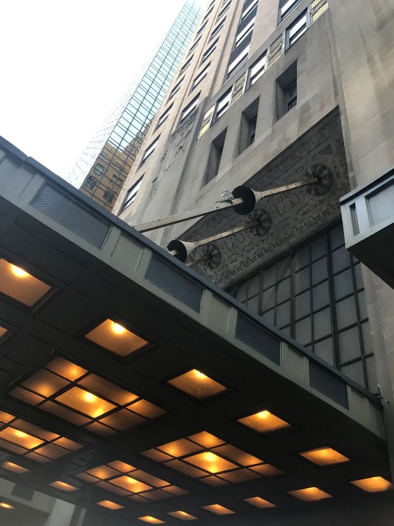 Looking up at a tall building from under its lit entrance canopy