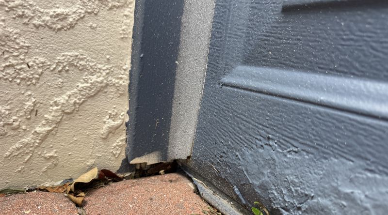 Bottom corner of a garage door where the worn seal leaves a gap at the frame