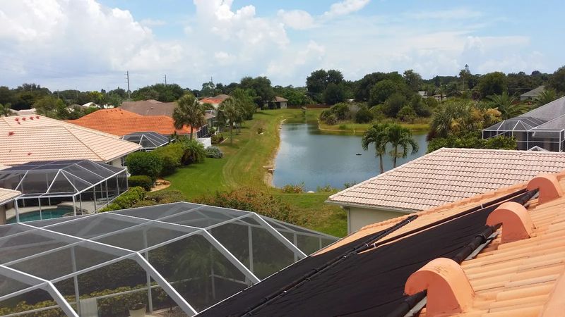 View across tile roofs and screened pool cages toward a pond in a Southwest Florida neighborhood